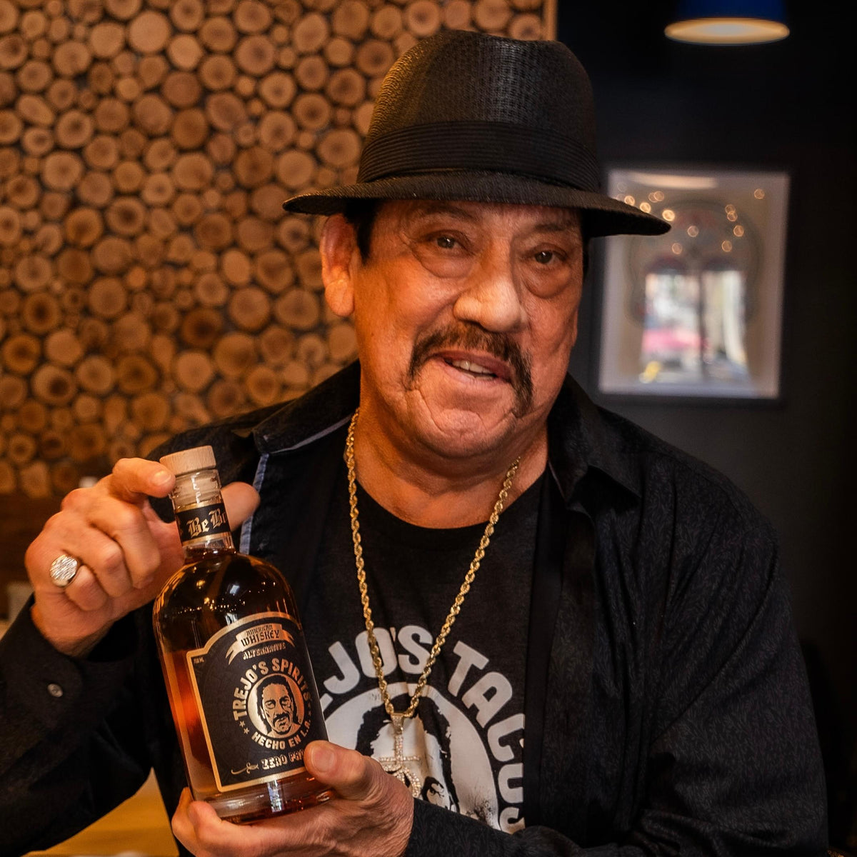 Danny Trejo holding a bottle of American Whiskey Alternative